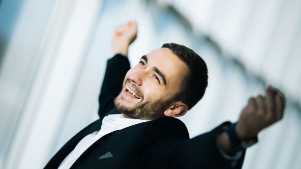 Happy Businessman executive raising fists in excitement in office