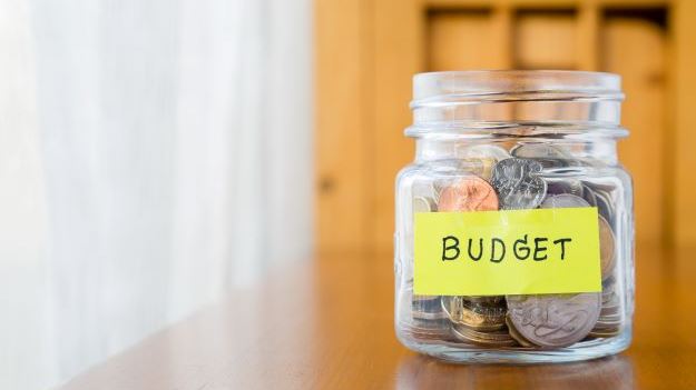 Coins in a jar with a post it note saying budget