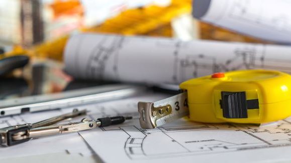 picture of measuring tape and compass lying on building plans