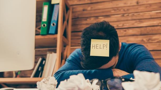 Man asking for help with postit on his head saying "Help"