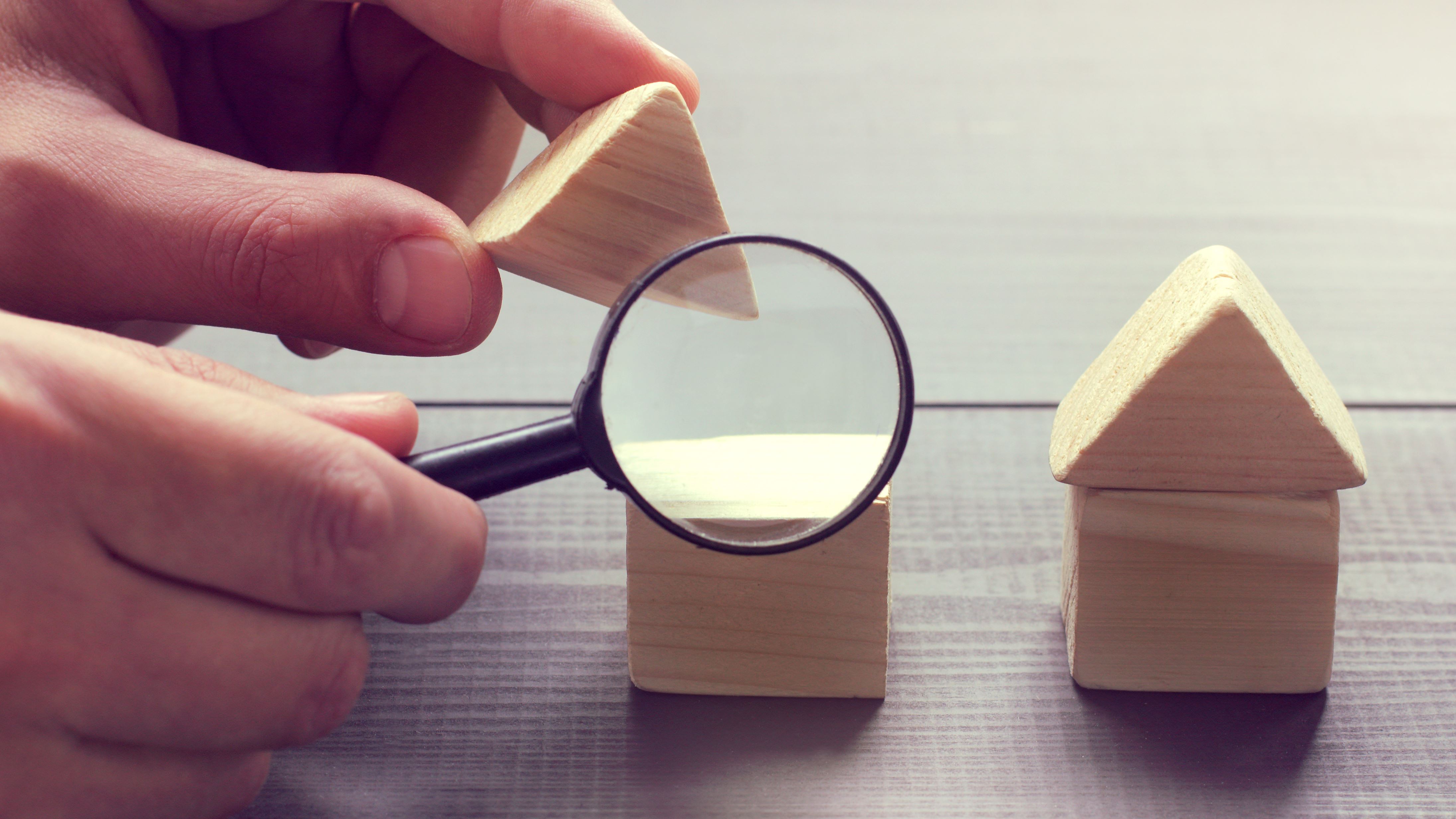 Hand building block houses with magnifying glass