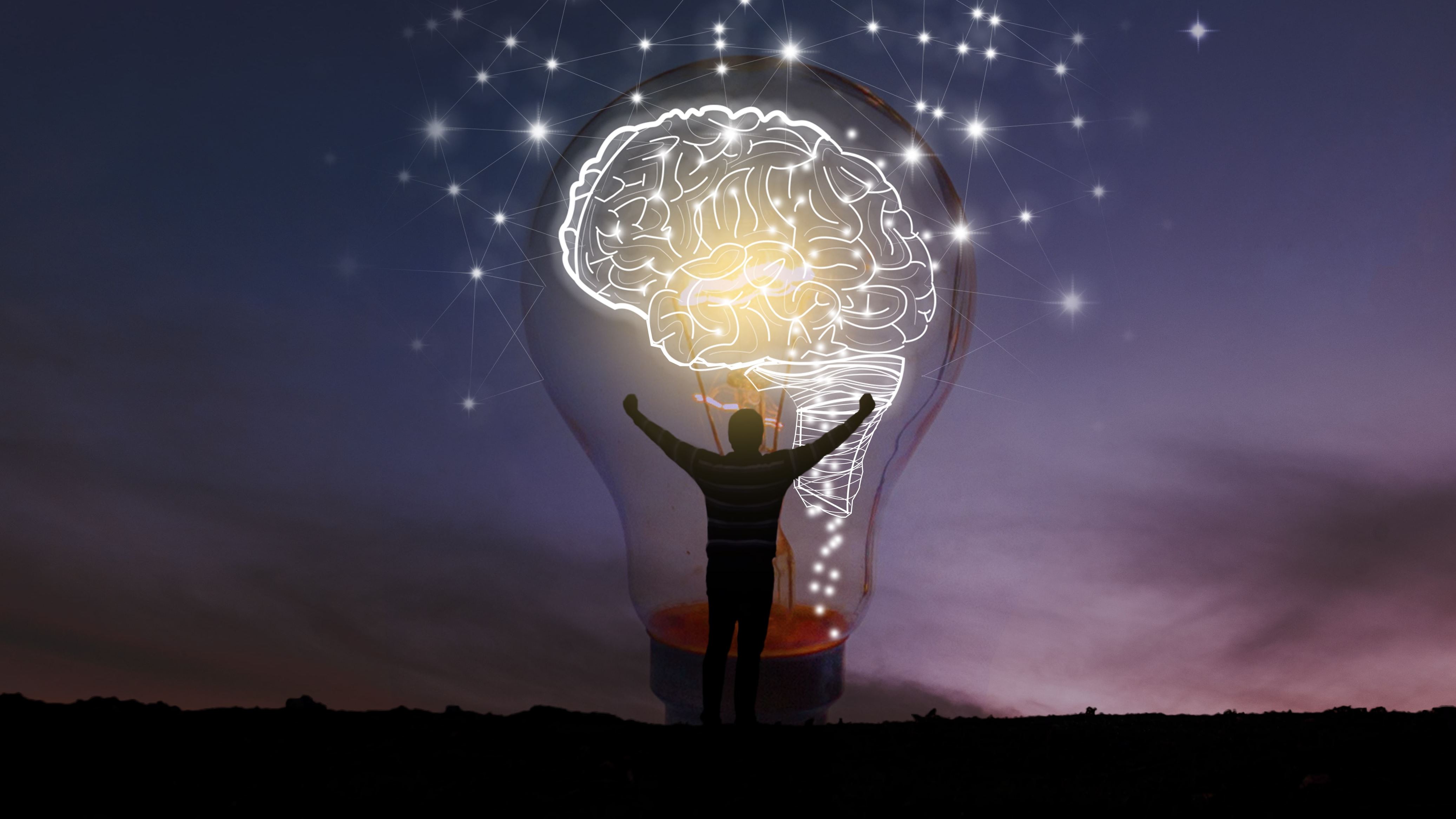 Man standing infront of giant light bulb with a brain inside it made of stars and lights