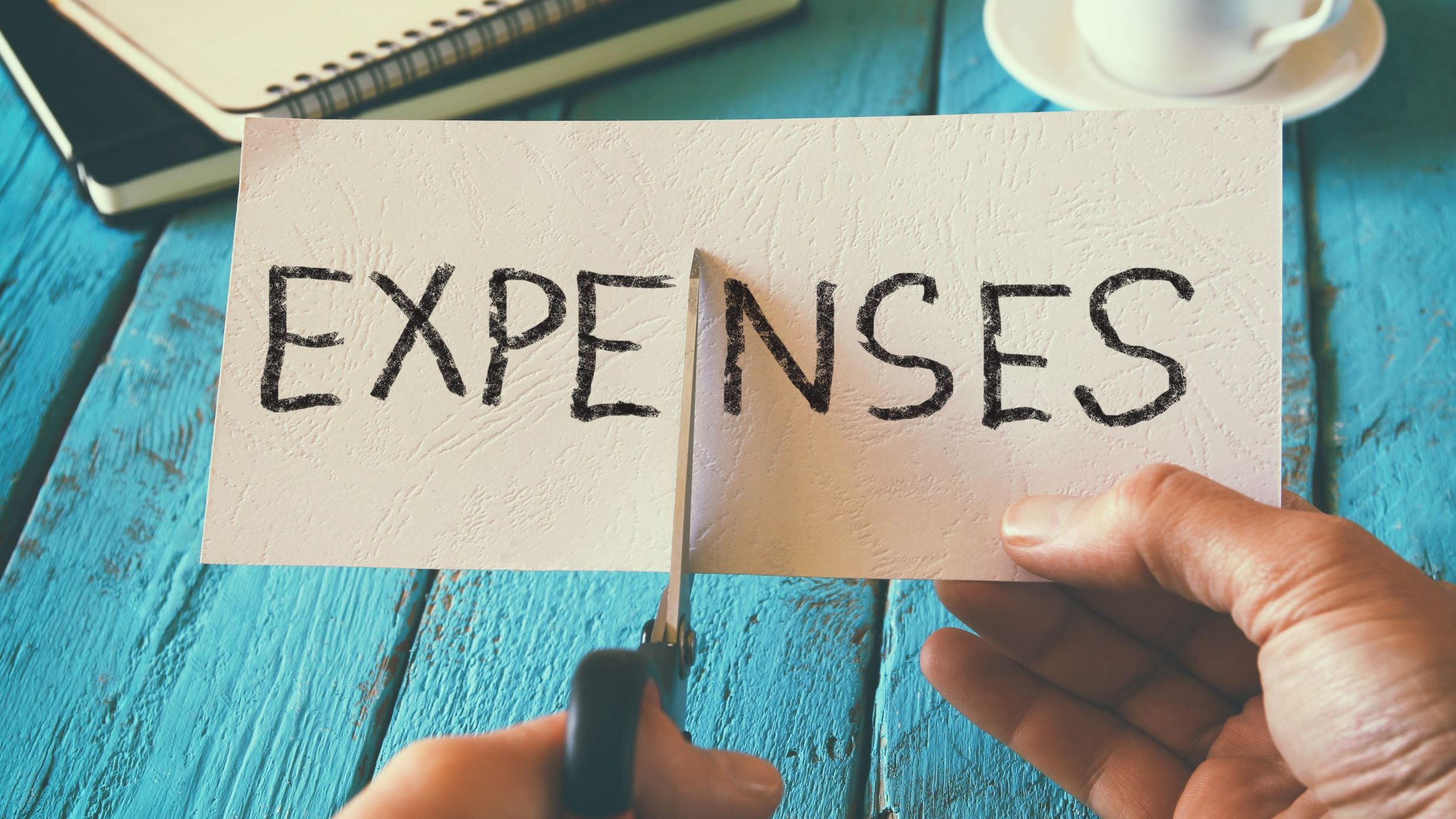 image of the word expenses being cut in half
