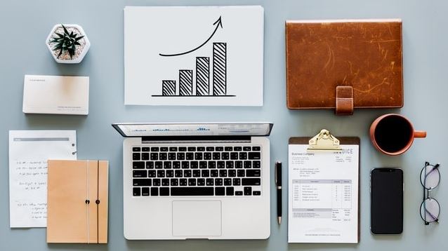 Desk with laptop, growth chart, checklist, phone and coffee