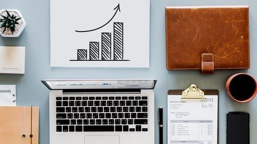 A table with a laptop and a graph displaying growth in the form of a bar chart