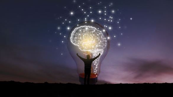 Man stood in front of lightbulb with giant brain inside of it