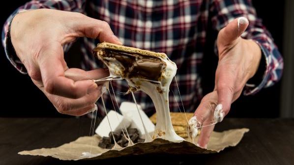 A messy smore half melted and sticking to an innovators fingers