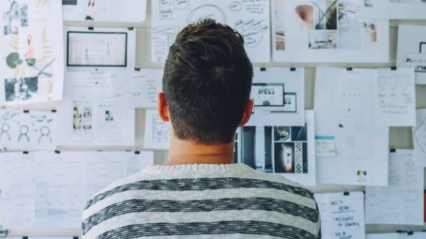 An employee looking at a wall with papers stuck to it trying to determine what qualifies as R&D in business