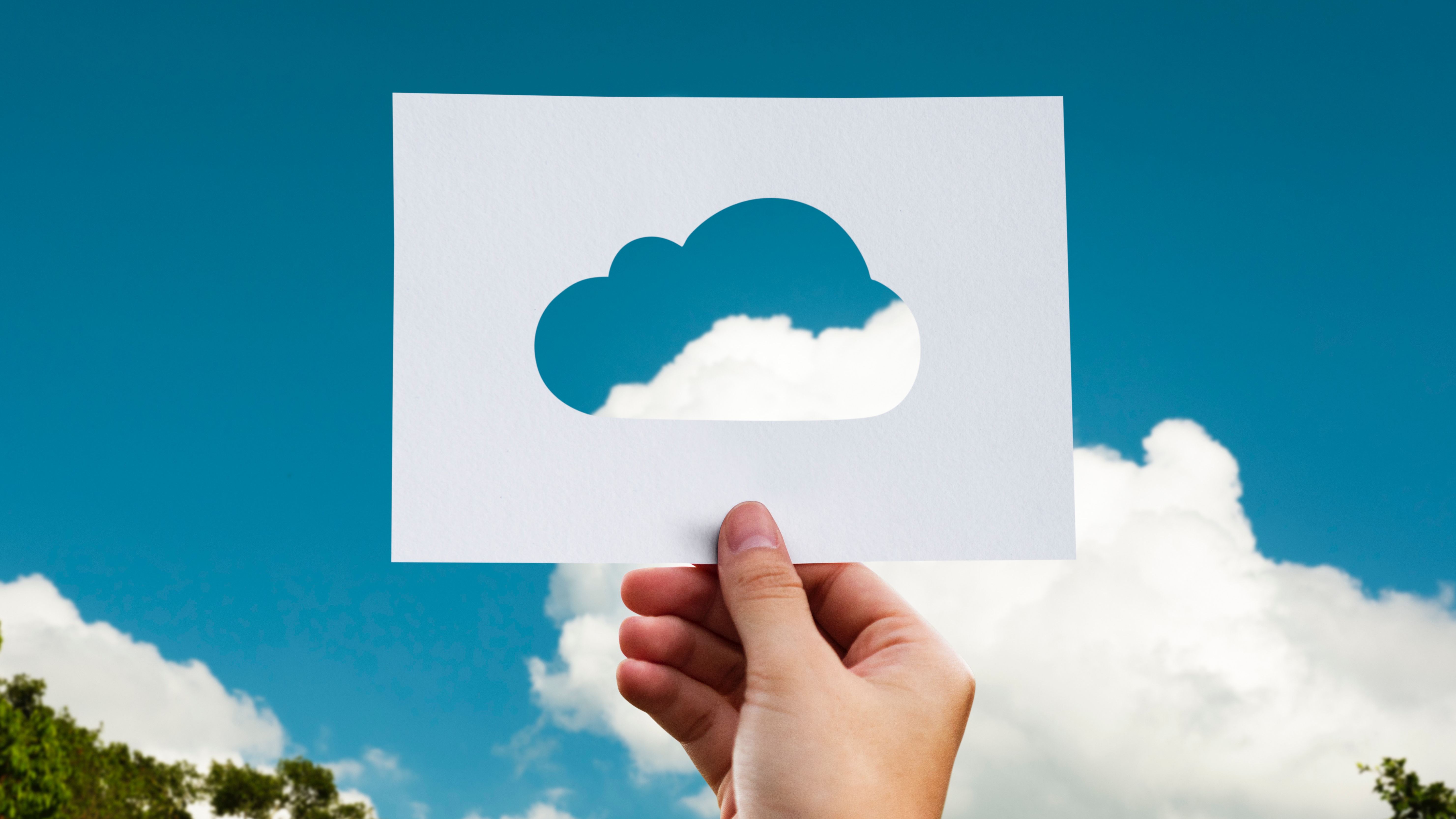 An R&D tax credit advisor holding a cut out image of a cloud against a blue sky