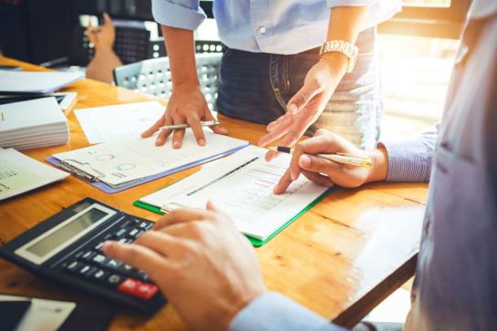 Colleagues Looking At Documents With A Calculator