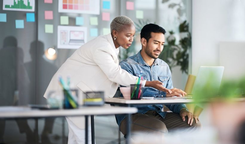 Female Colleague Pointing To Male Colleague's Laptop